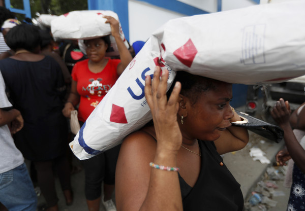 배급 받은 쌀을 이고 가는 아이티 국민 [사진=AP, 연합뉴스]