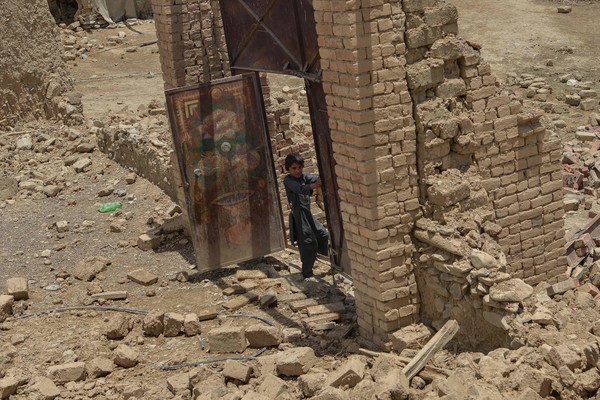 한 소년이 지진으로 피해를 입은 집 문 옆에 서 있다. [사진=AFP/연합뉴스]