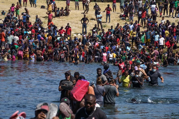 2021년 9월 19일 미국 국경의 야영지에 머물고 있는 아이티 이민자들이 멕시코에서 음식과 물을 얻기 위해 리오 그란데 강을 건너고 있다. [사진=AFP/연합뉴스]